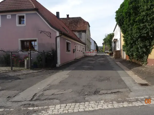 Asphaltierte Straßen und Gehwege. Im Hintergrund Häuser.