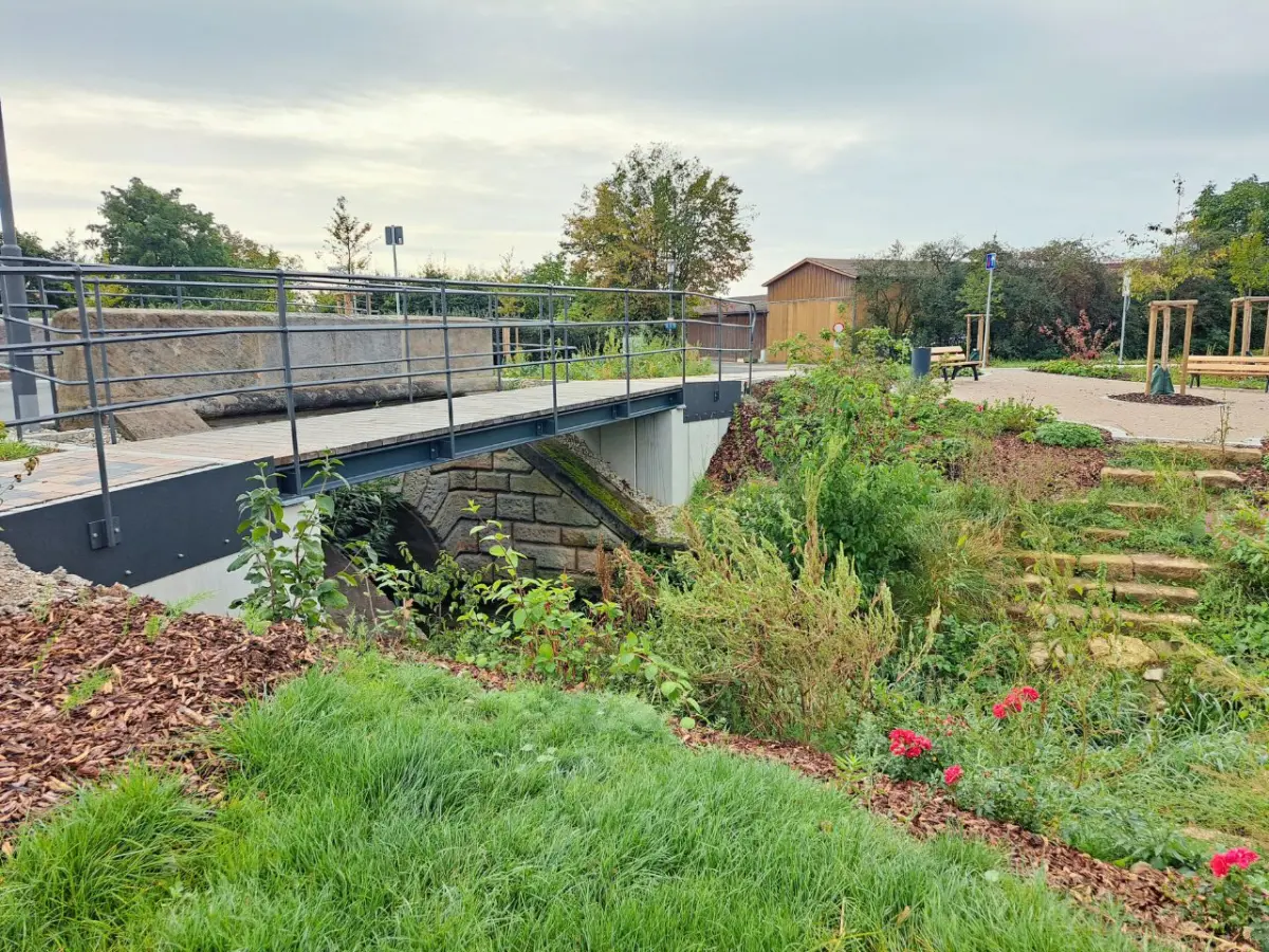 Fußgängerüberweg und westliche Sandsteinbrücke über einen renaturierten Bach.