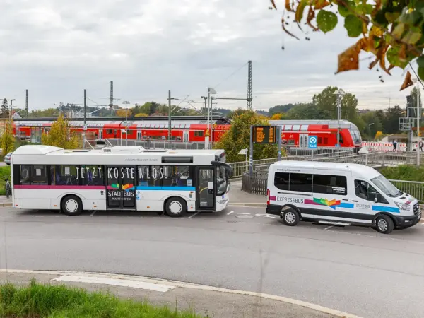 Link ein Bus und recht ein Kleinbus. Im Hintergrund ein Zug.