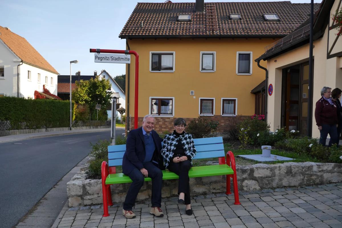 Mann und Frau sitzen auf Mitfahrbank