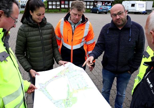 5 Personen halten Bauplan in der Hand und diskutieren darüber