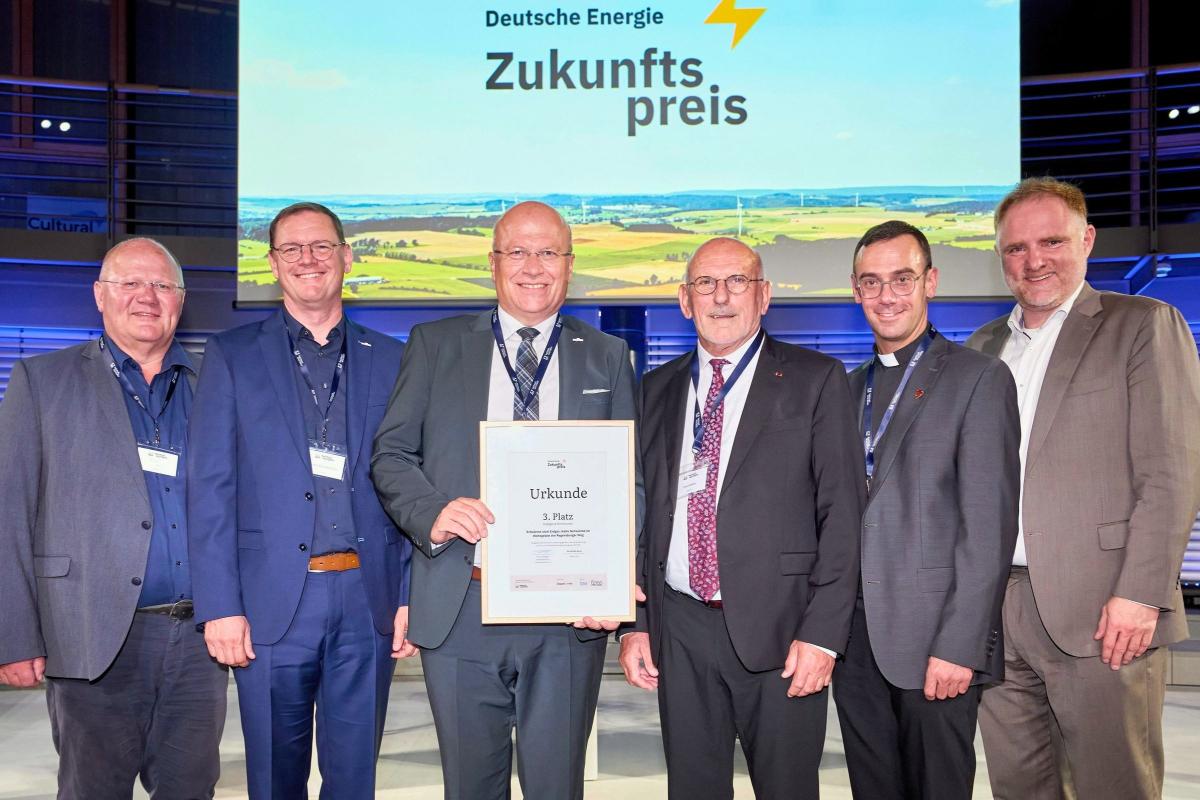 Sechs Männer stehen auf Tribüne und halten lächelnd Urkunde in der Hand.