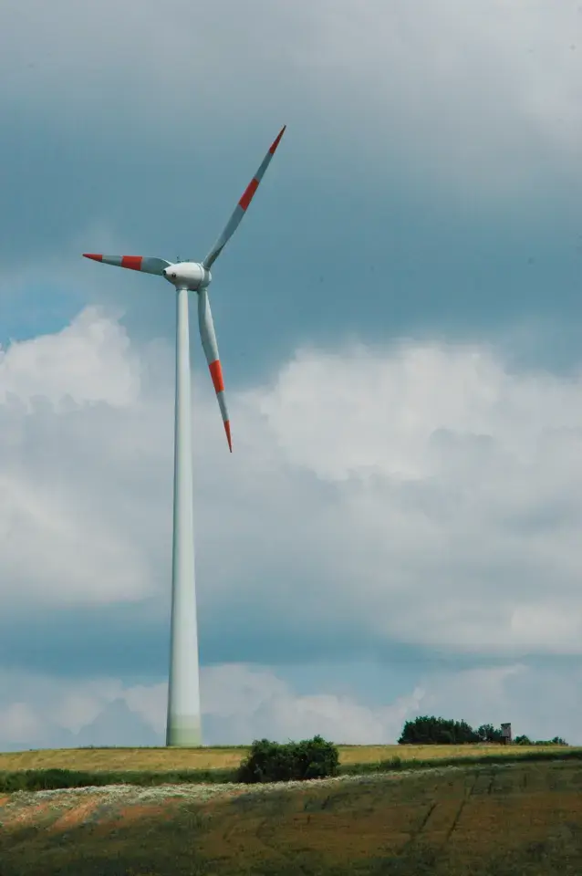 Windrad auf Feld bei bewölktem Wetter.