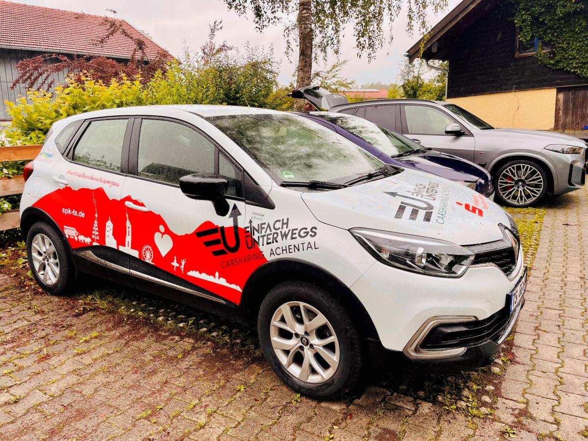 Weiß-rotes Carsharing Auto auf einem Parkplatz.