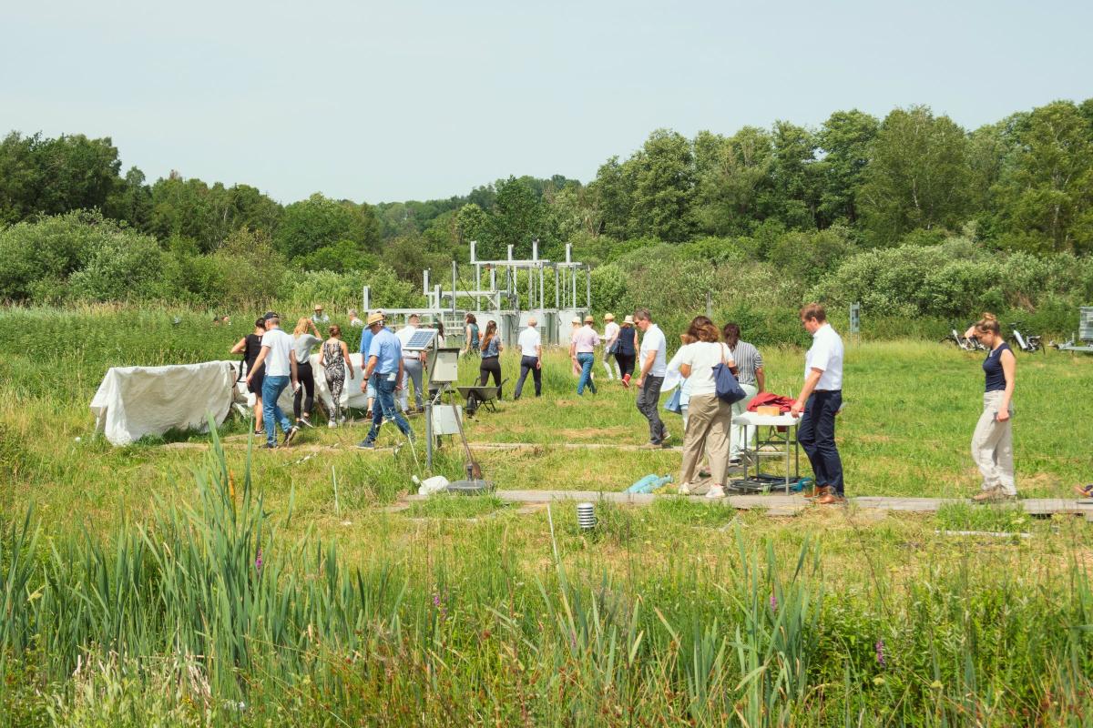 Menschen sehen sich Messstationen in der Landschaft an.