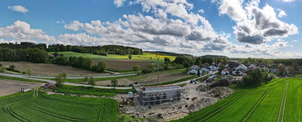 Luftaufnahme vom Bau des Heizhauses. Im Hintegrund ländliche Gegend. Rechts Dorf Hofham.