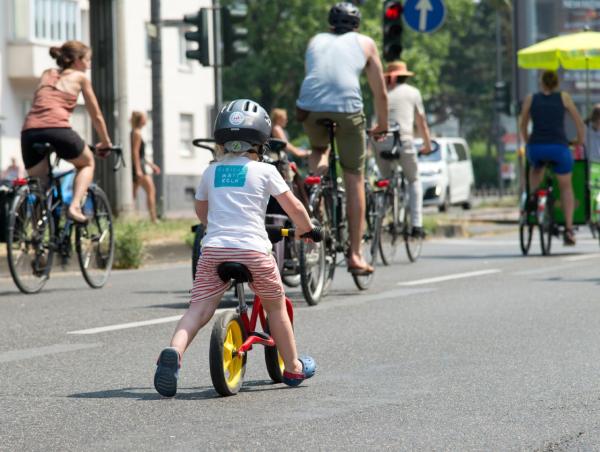 Kinder und Erwachsene fahren auf einer Straße Fahrrad.