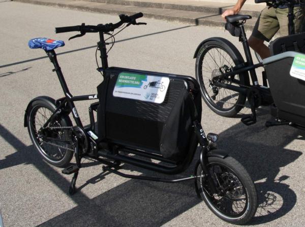 Schwarzes Lastenfahrrad auf einer Straße.