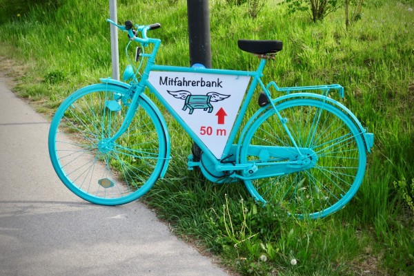 Schild zeigt Weg zur nächsten Mitfahrbank