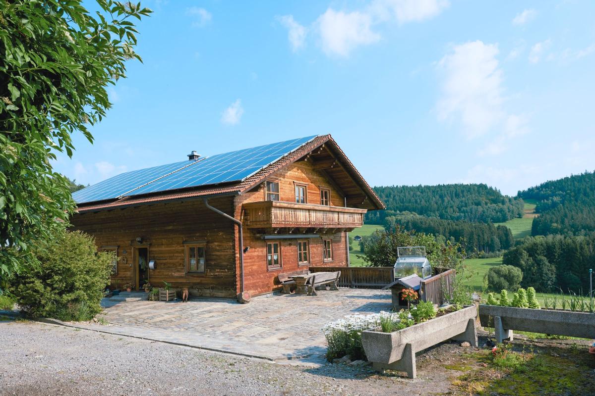 Holzhaus vor Mittelgebirgslandschaft