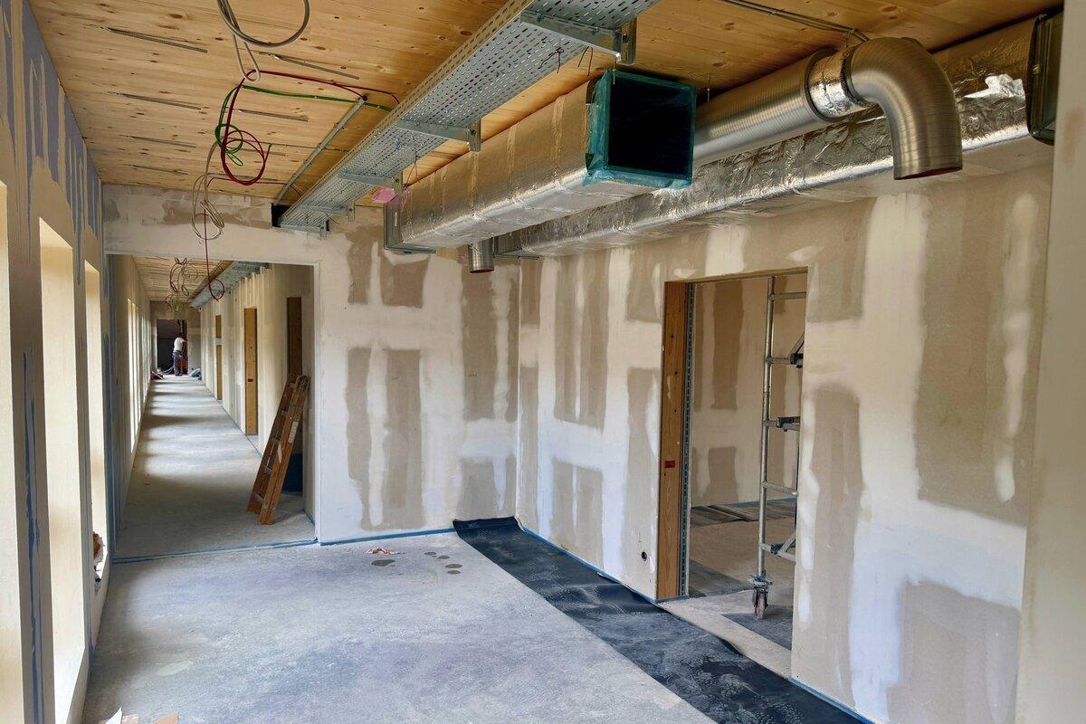 Rohbau mit Holzdecke und Lüftungsanlage.