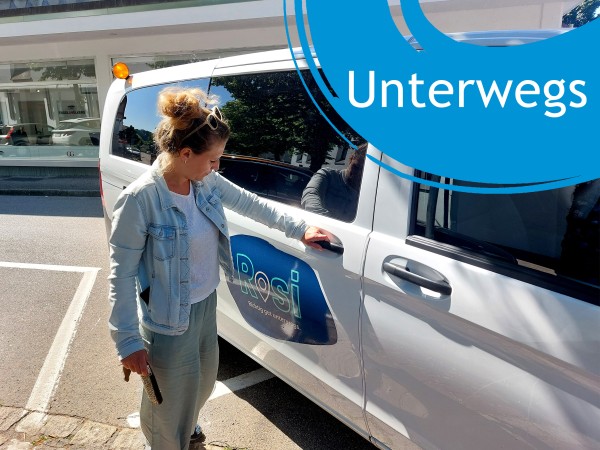 Frau öffnet Tür eines Kleinbusses, daneben der Schriftzug "Unterwegs"