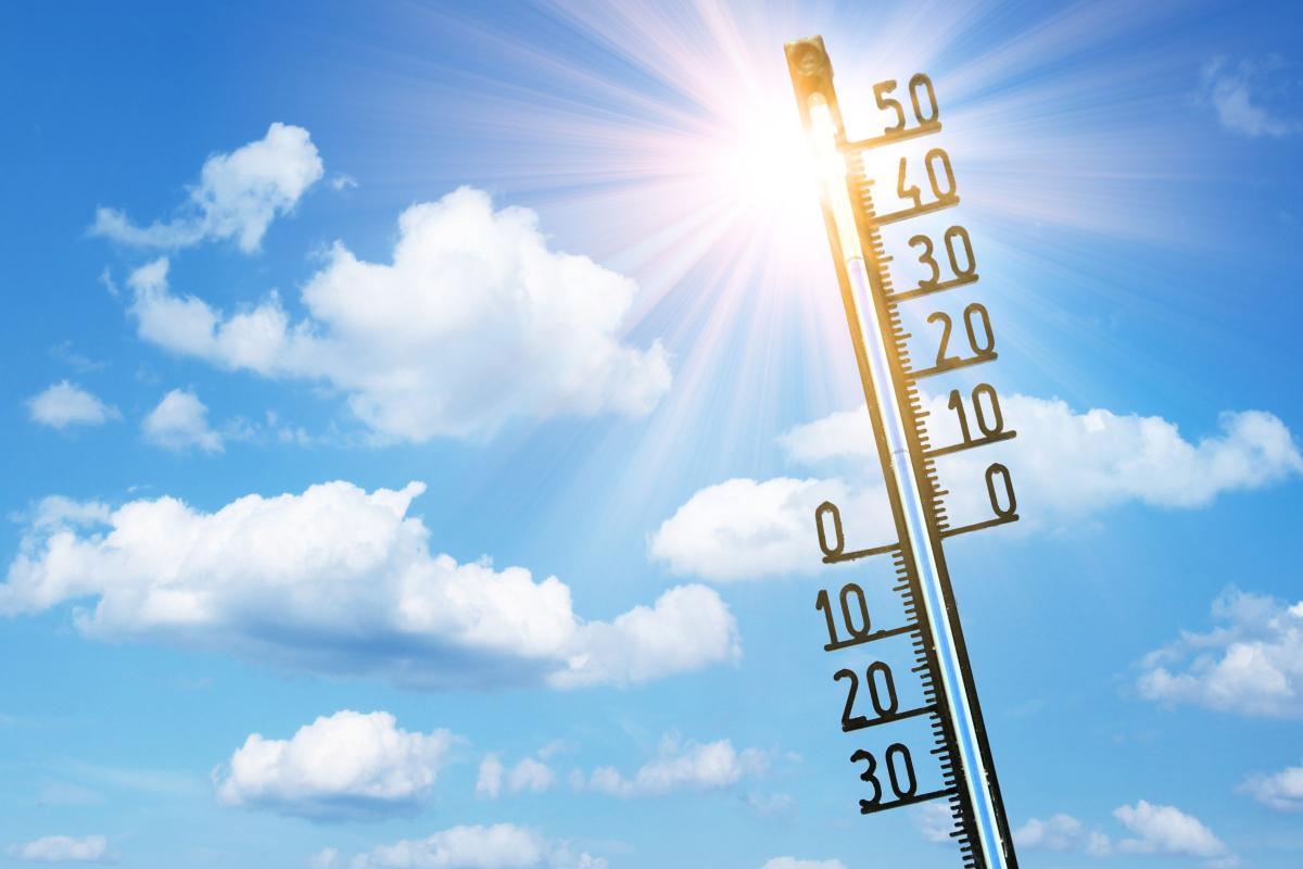 Thermometer vor einem sonnigen Himmel mit einzelnen Wolken