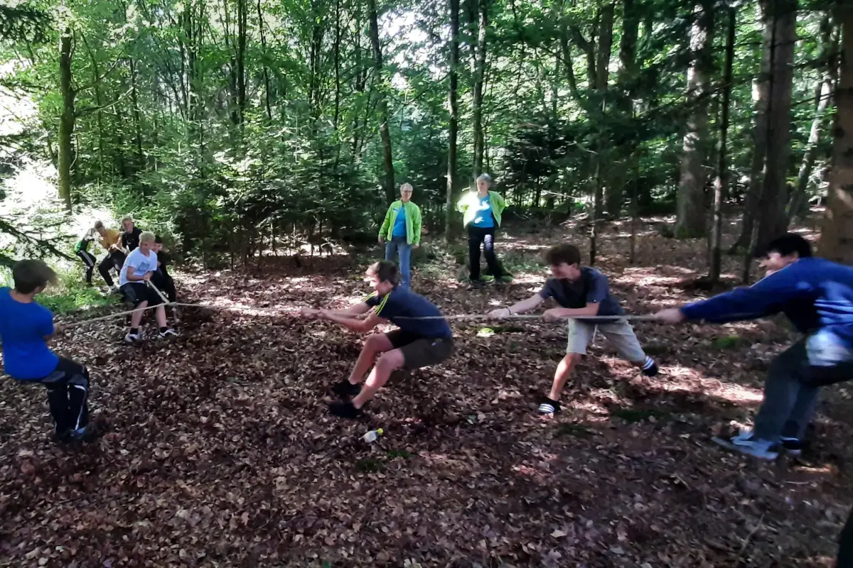 Klimaschutz spielerisch entdecken steht im Fokus des Projekts - Kinder speilen im Wald Tauziehen.