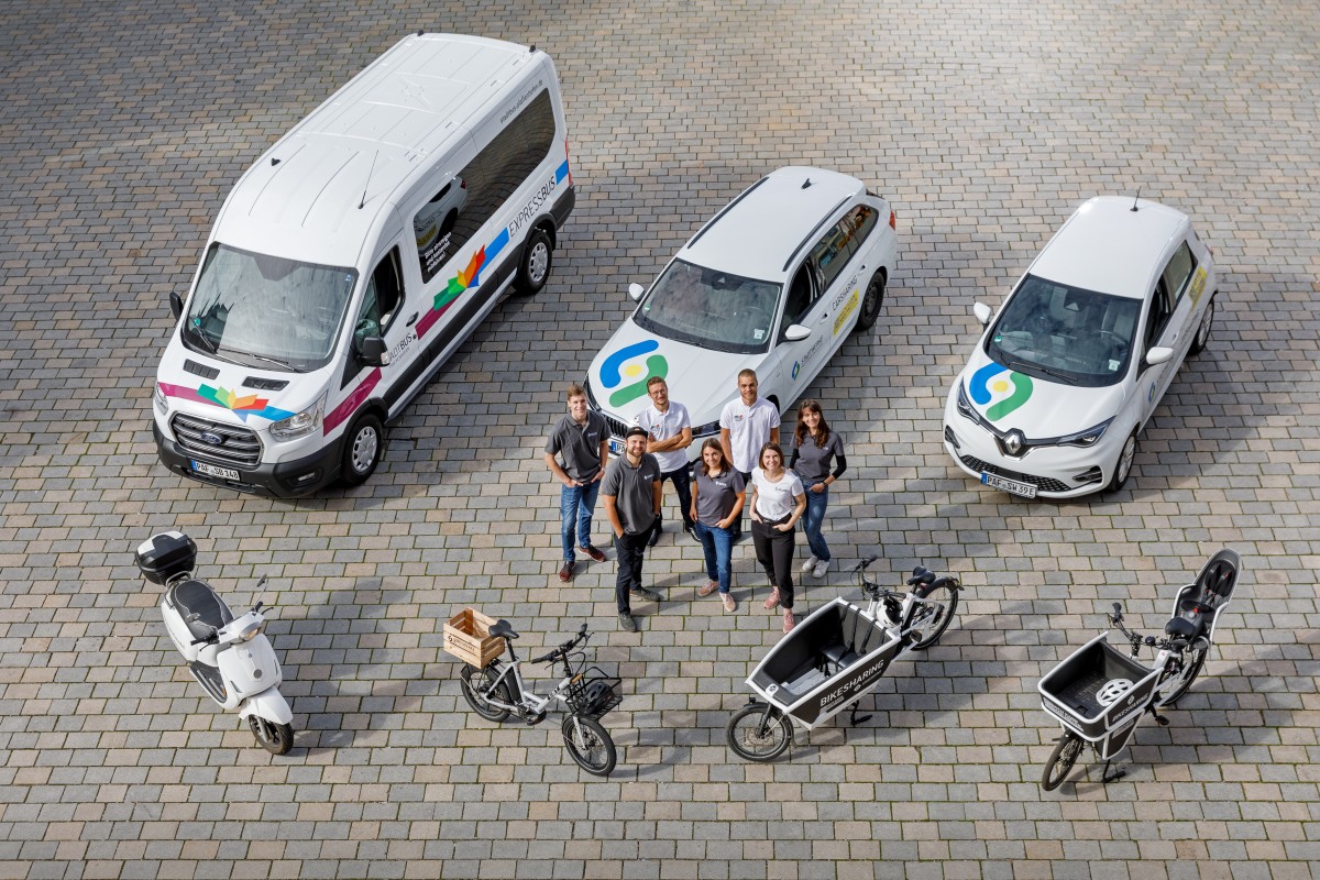 Mitarbeitende des "Team Mobilität" stehen neben Kleinbus, Carsharing- und Bikesharing-Fahrzeugen