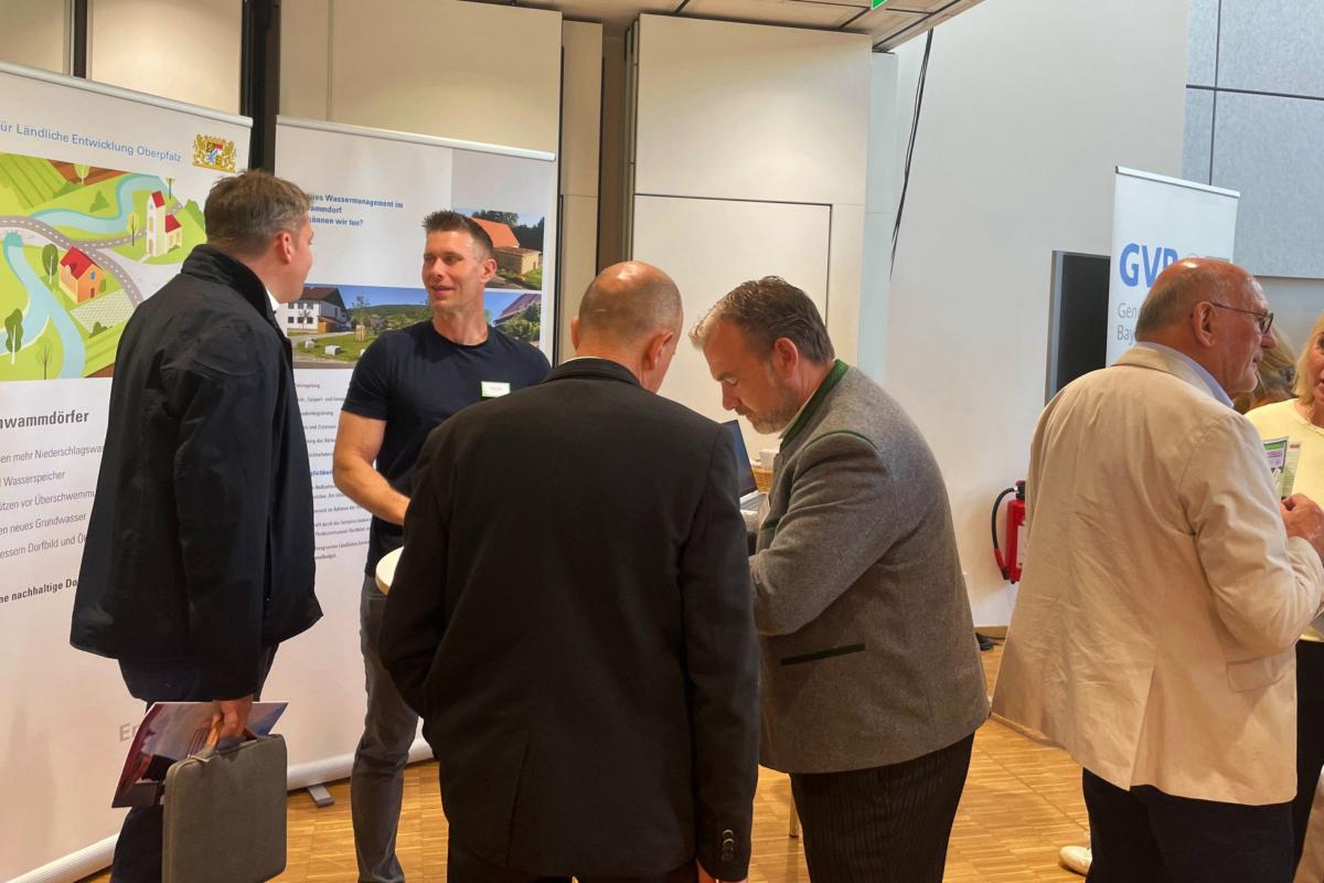 Menschen im Gespräch bei einem Messestand.