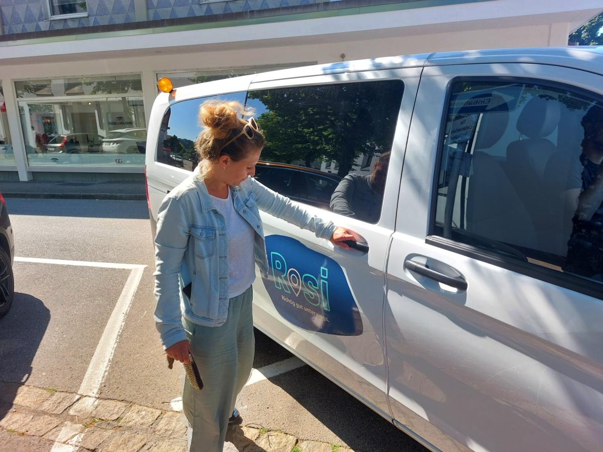 Frau öffnet Tür eines Kleinbusses.