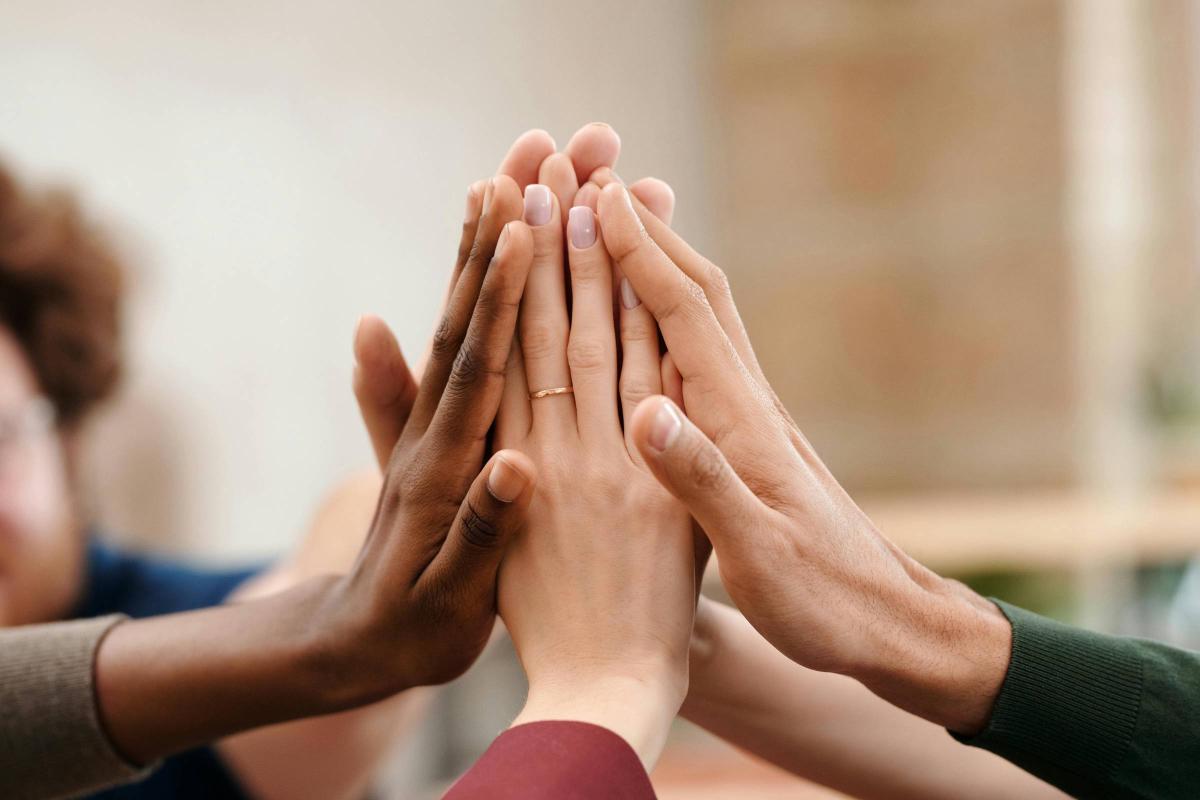 Fünf Hände von fünf Personen geben sich ein High-Five.