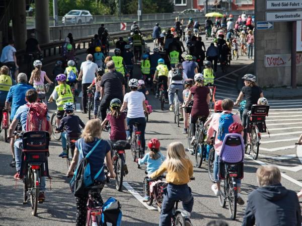 Kinder und Erwachsene fahren auf einer Straße Fahrrad.