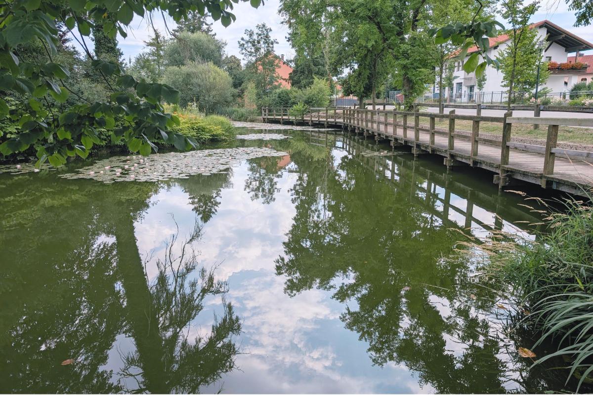 Steg entlang eines Dorfsees.