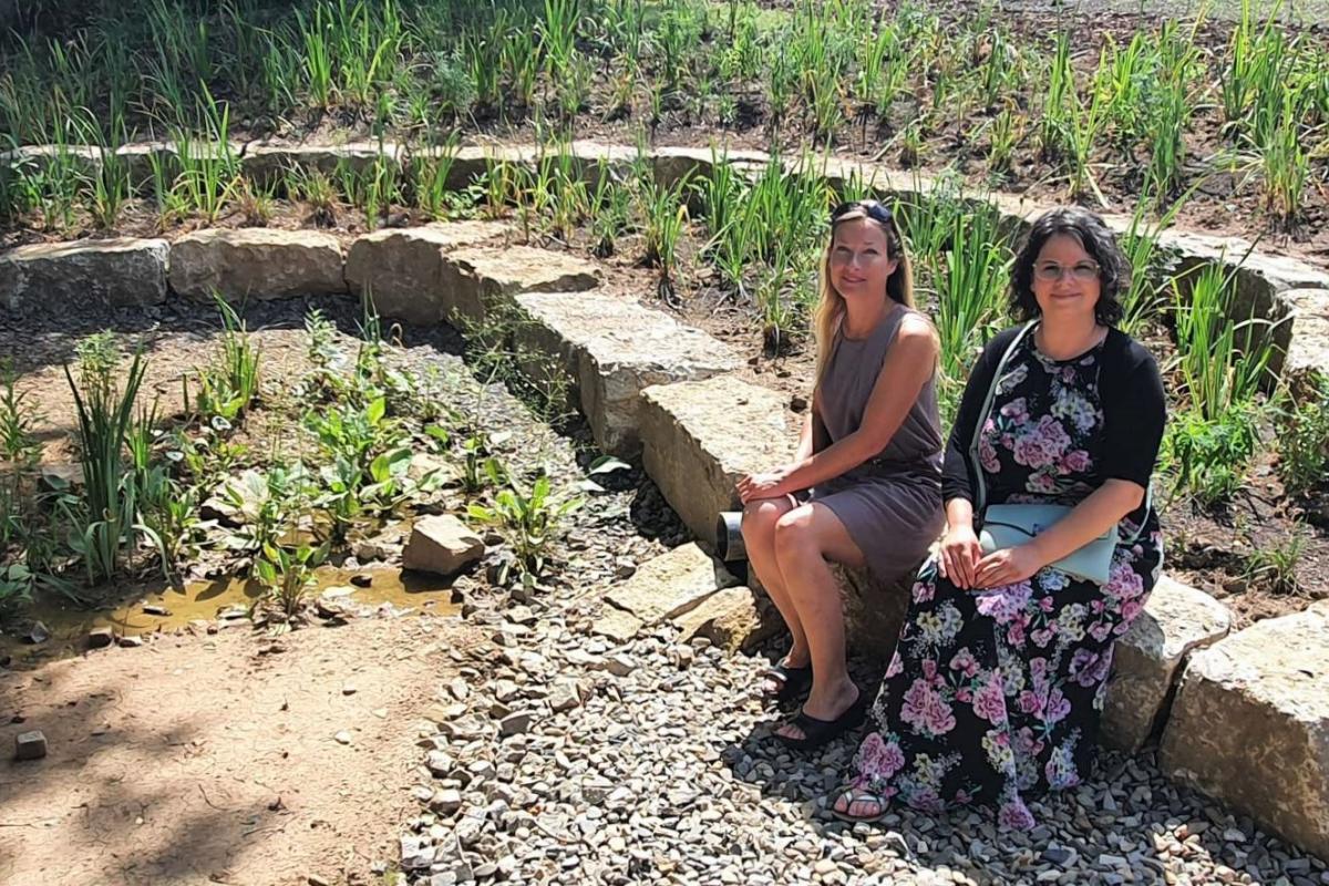 Zwei Frauen sitzen auf terrassiertem Becken im Lilienfeld.