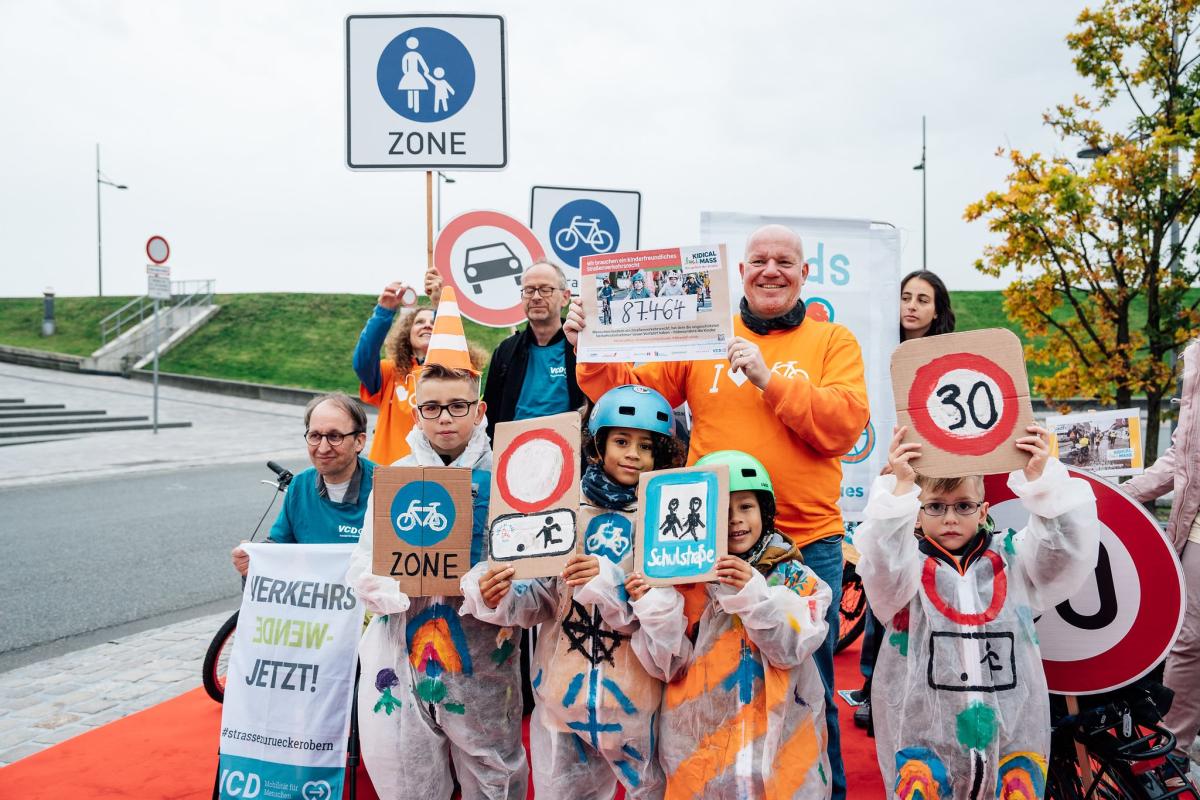 Kinder halten selbstgemalte Verkehrsschilder in die Luft.