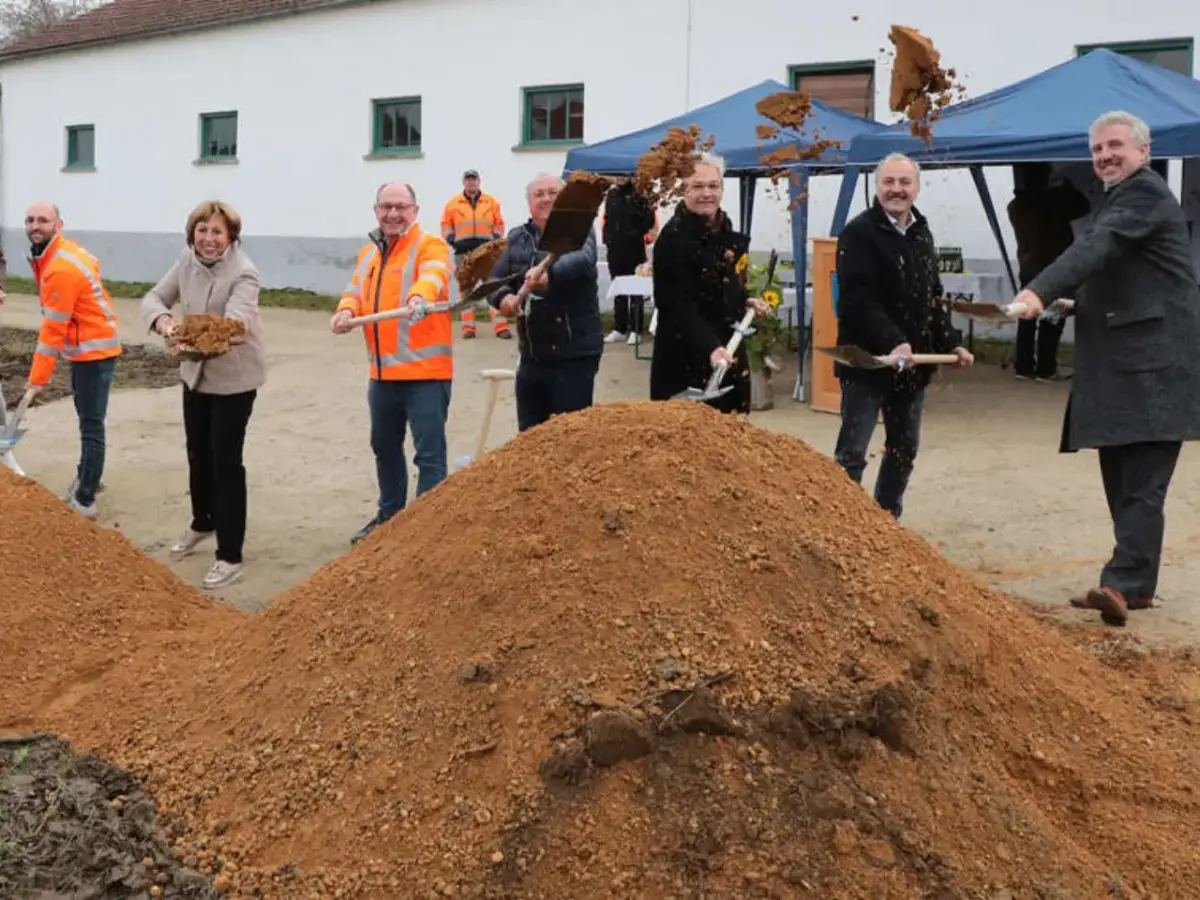 Sieben Personen stehen hinter Erdhaufen und werfen mit Spaten Erde in die Luft.
