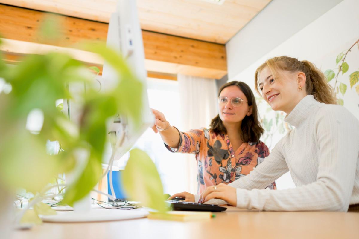 Zwei Mitarbeiterinnen analysieren gemeinsam Inhalte am Bildschirm